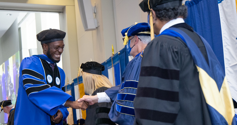 Doctoral graduate shakes hands with the chancellor