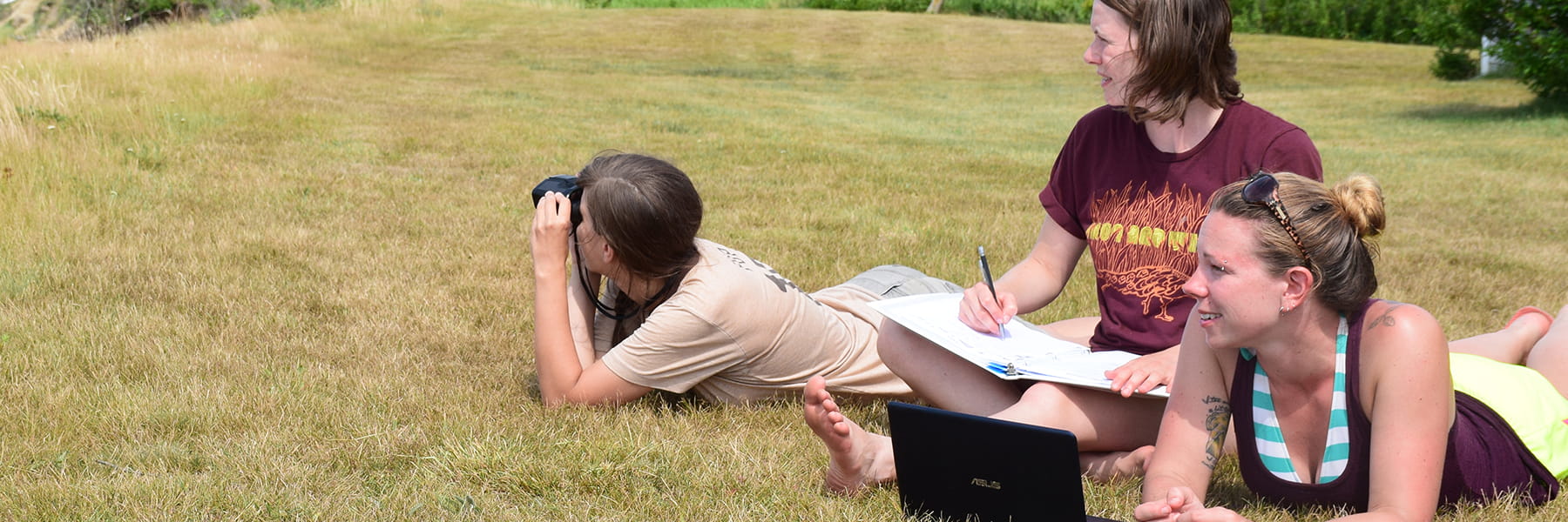 Student at Nantucket Field Station lawn looks through binoculars.