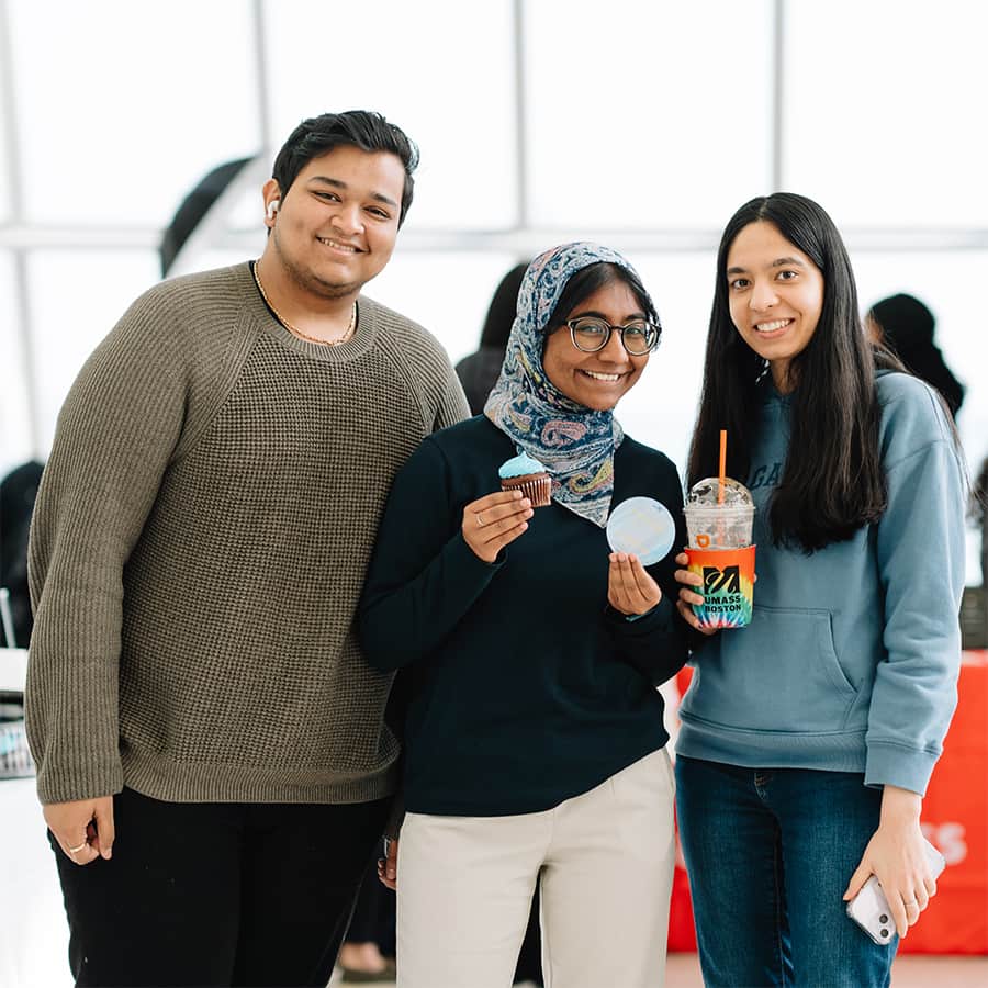 Trio of students holding a cupcake and UMass Boston memorabilia.