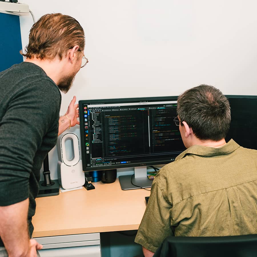Students reviewing code on computer with Professor.