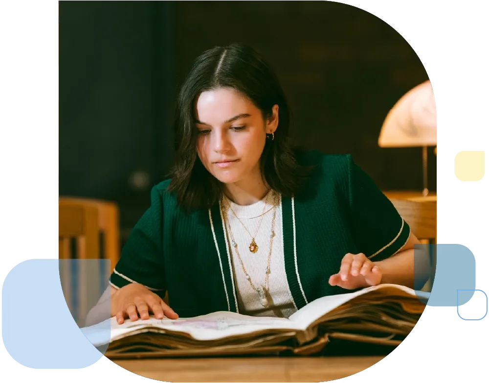 Student looking over a book of historic archives.