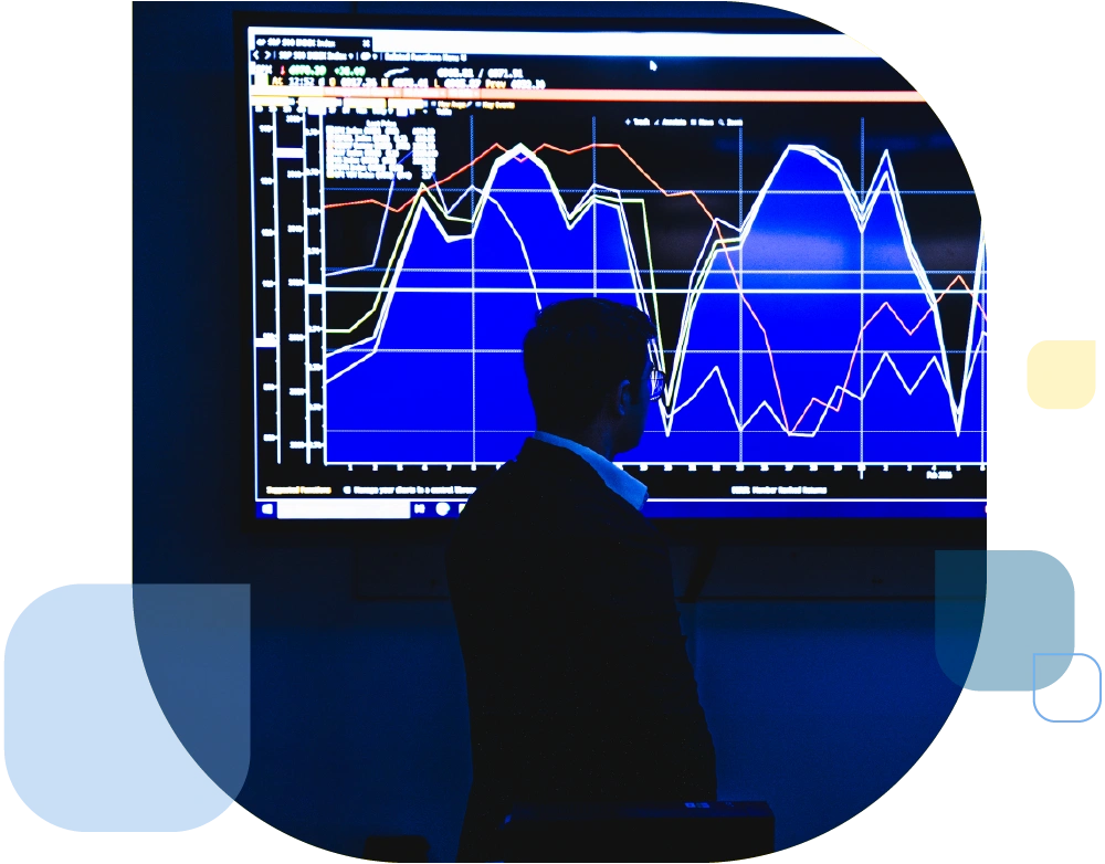 person wearing glasses in business attire looking at analytics chart on screen in blue hue