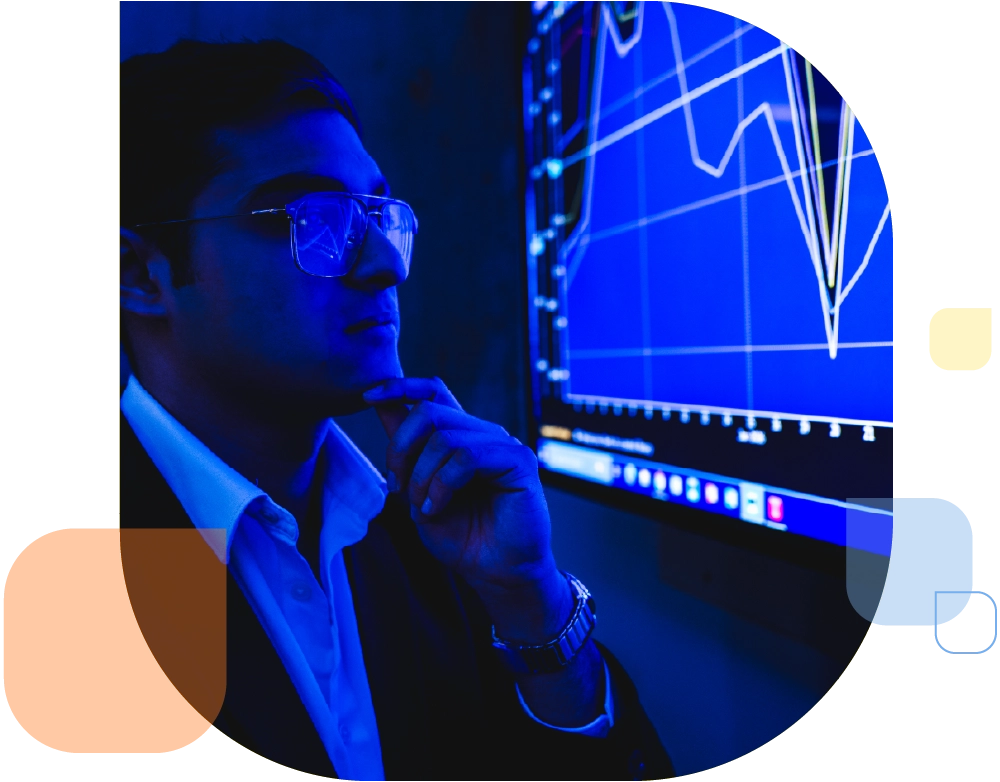 person wearing glasses in business attire looking at analytics chart on screen in blue hue