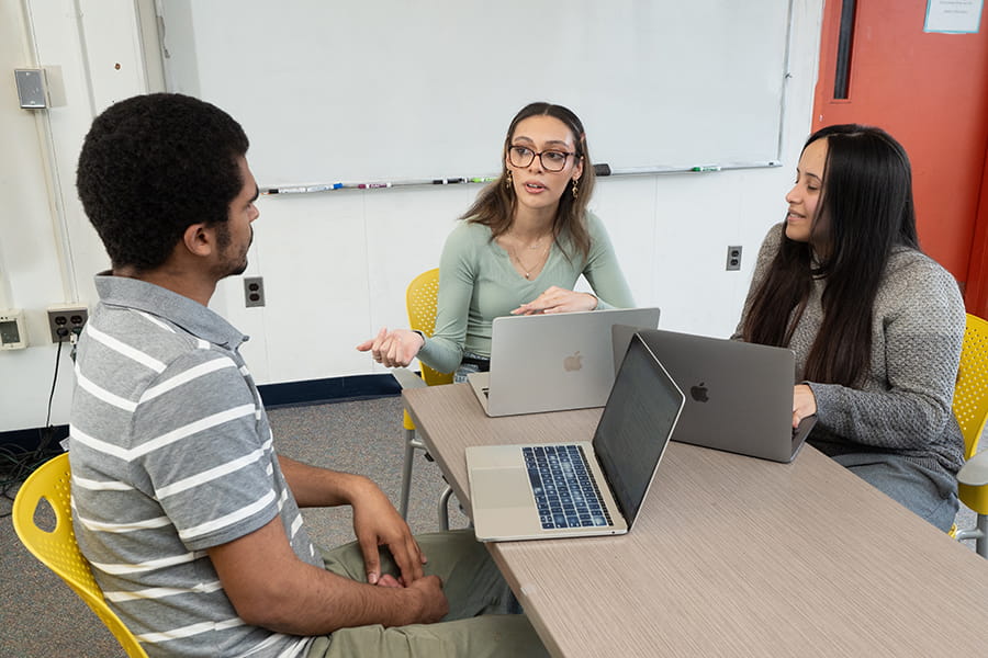 Three students working and speaking together.