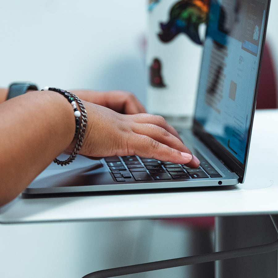 Close up of student's hands working on laptop.