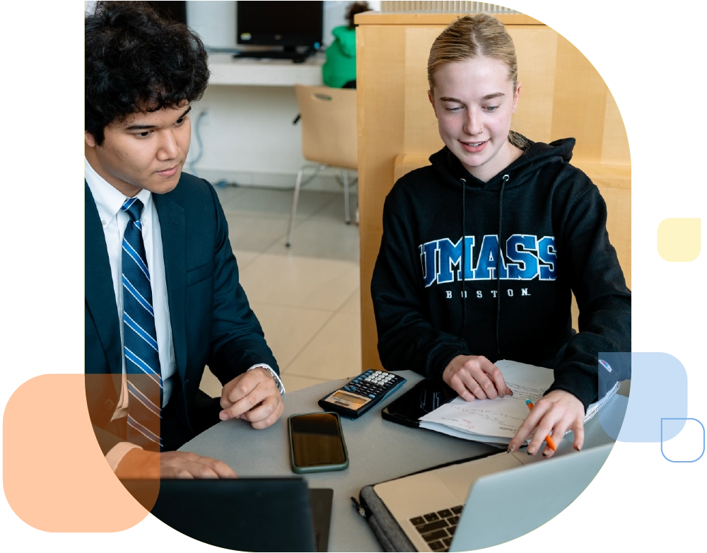 business school students at table with calculator and notepad reviewing laptop