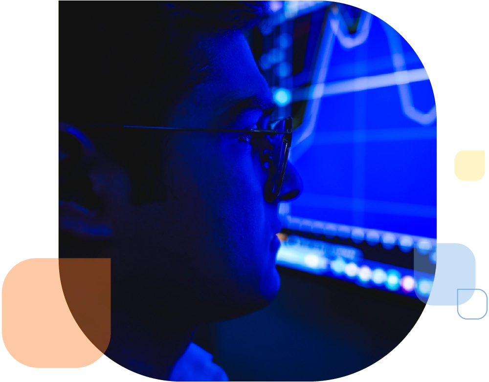 person wearing glasses in business attire looking at analytics chart on screen in blue hue