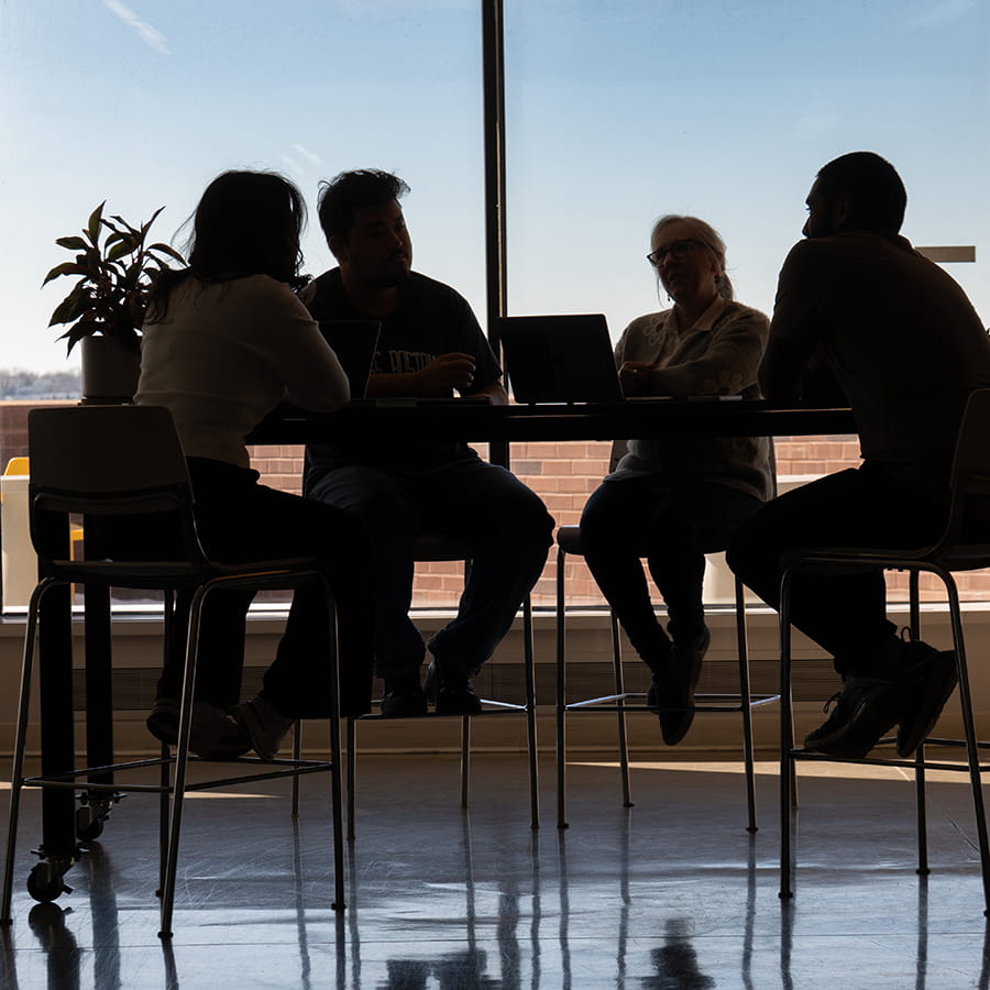 silhouette of students sitting on high top chairs in the VDC toward dusk