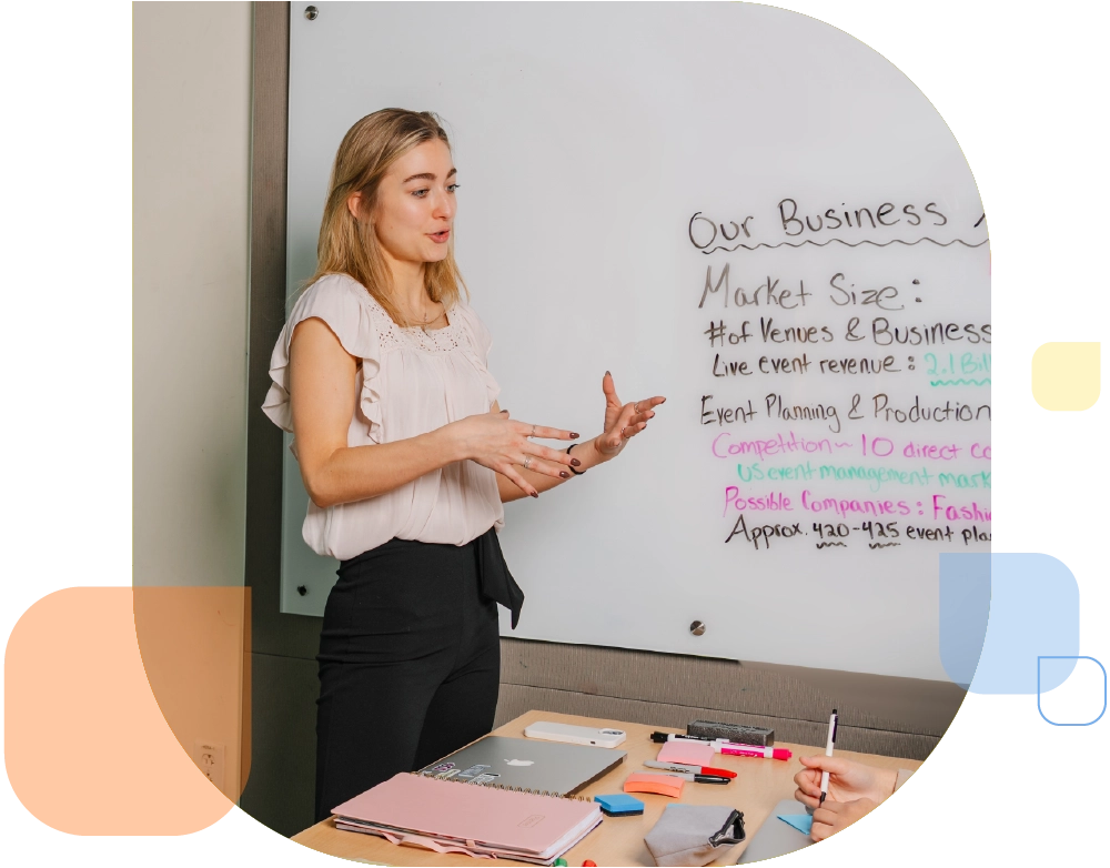 student in casual business attire leads a session in front of a whiteboard