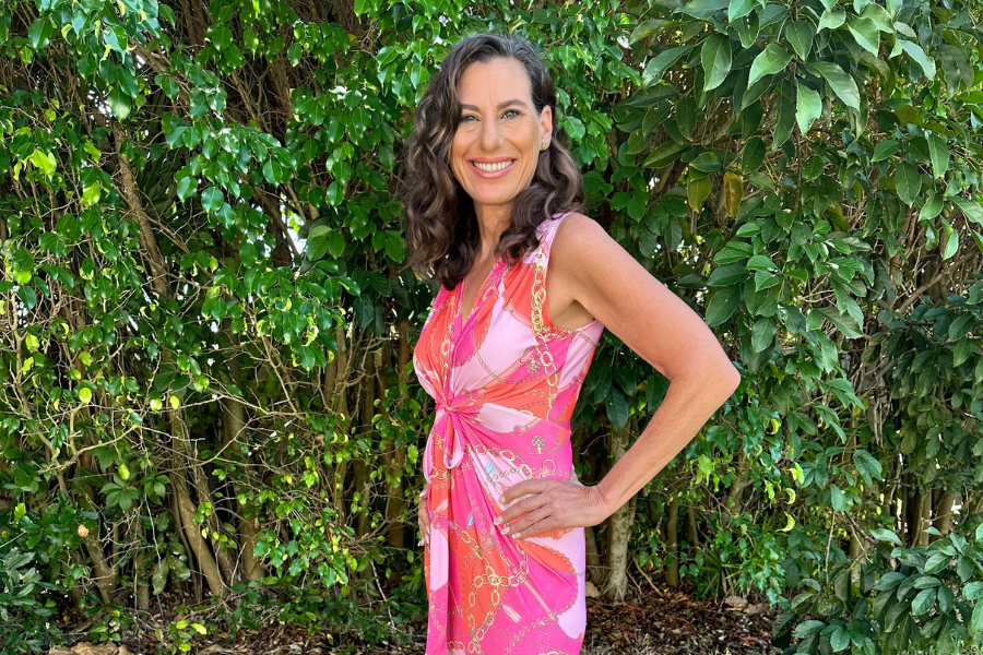 A woman in a pink dress standing in front of trees