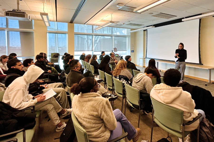 Alumna Kelly Manning stands in the front of a classroom, speaking to students