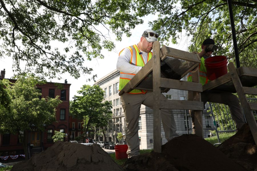 Image of staff member sifting through items at the dig