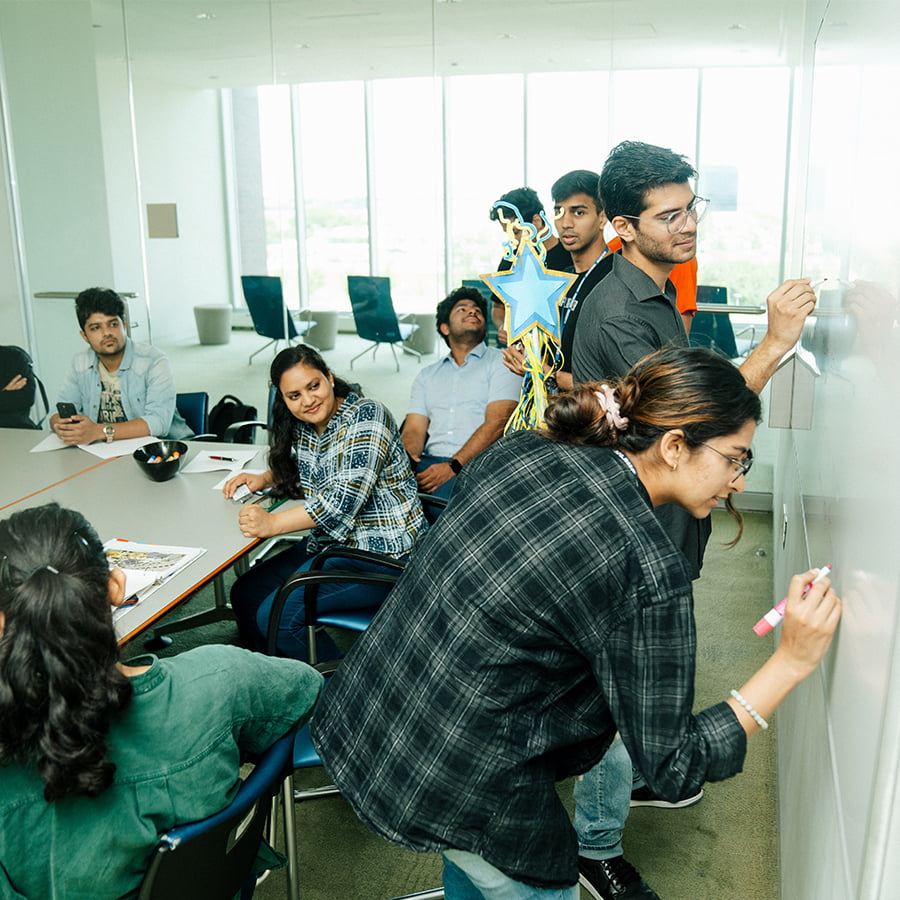 Graduate students write on whiteboard in seminar room.