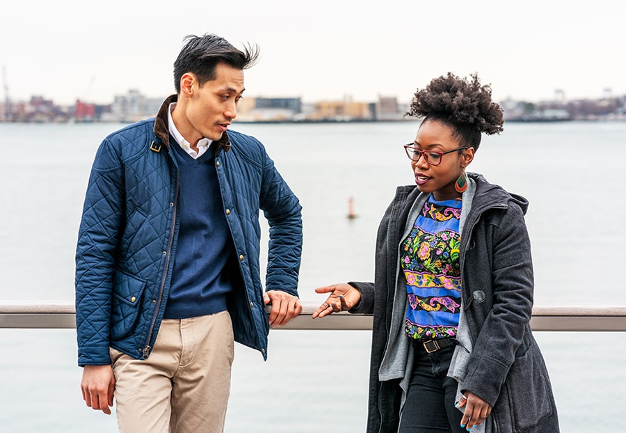 young urban man and woman in light jackets chatting in Boston's harbor area