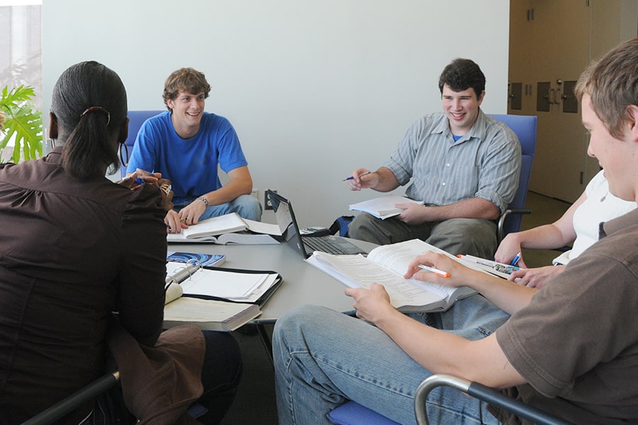 Group of student discuss classwork in a circle in study lounge.