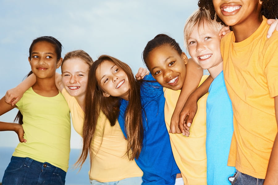 Group of school age children stand together.