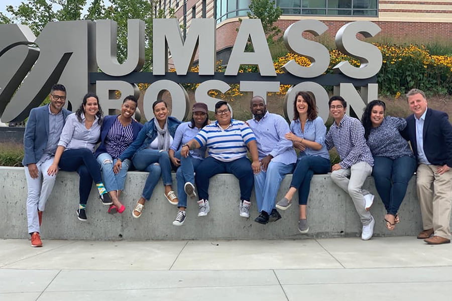 Leadership in Education students in front of UMass Boston sign.