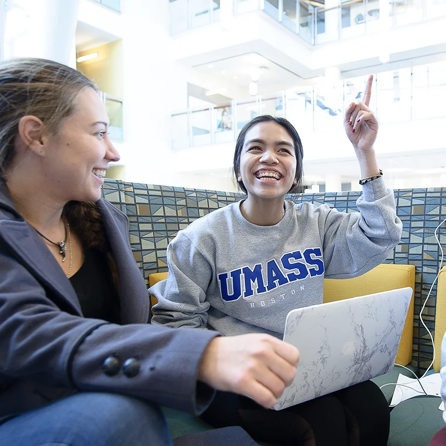 Students discuss presentation in ISC lounge, one raises hand.