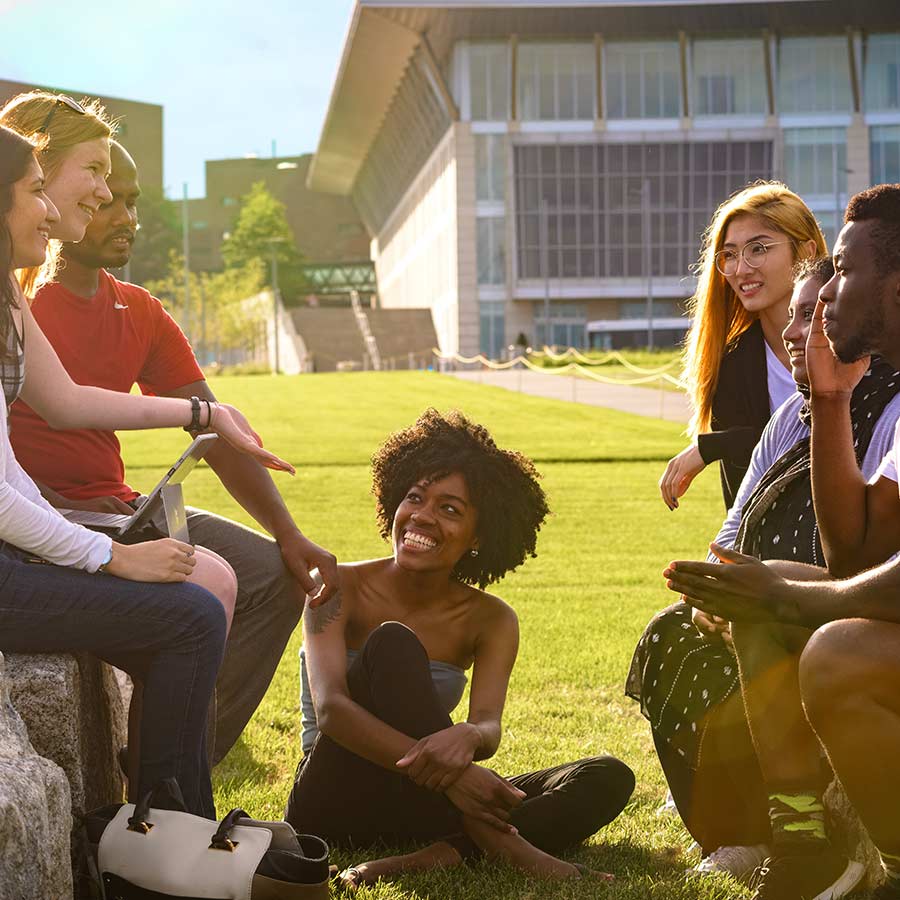 Students sitting on campus lawn with Campus Center in back
