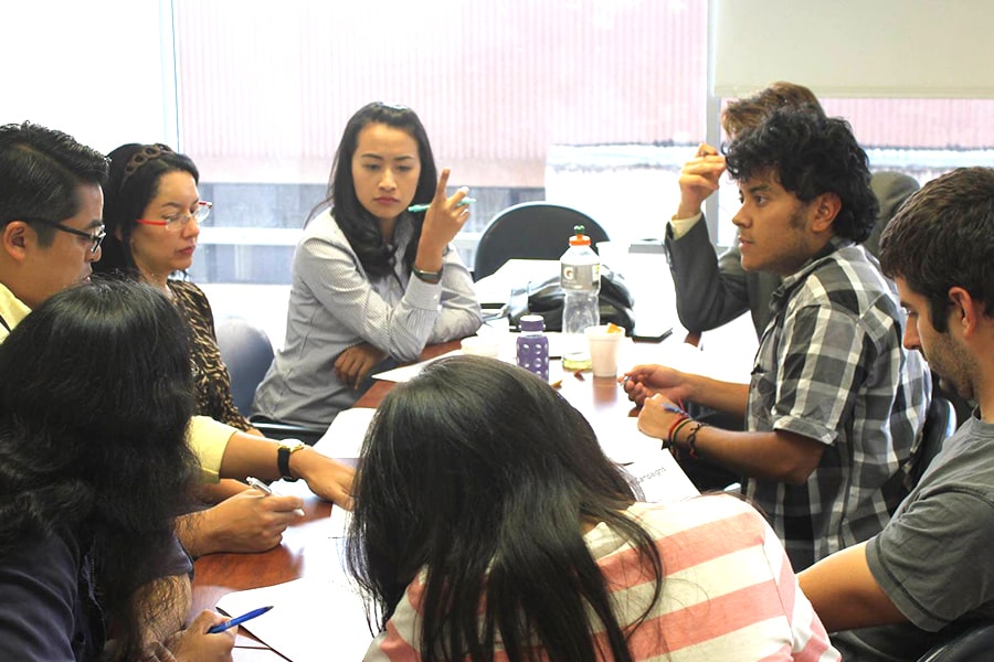 students talk around a table in a classroom.