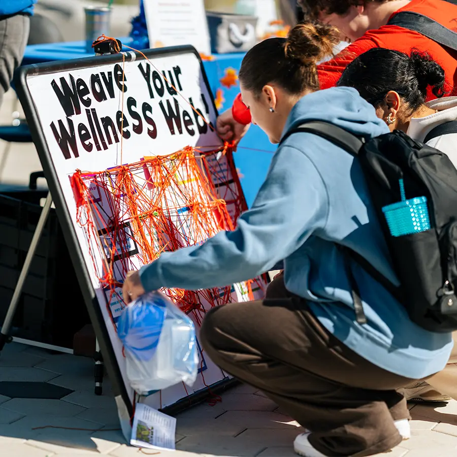 Students at a wellness info board at a wellness fair in the quad at UMass Boston.