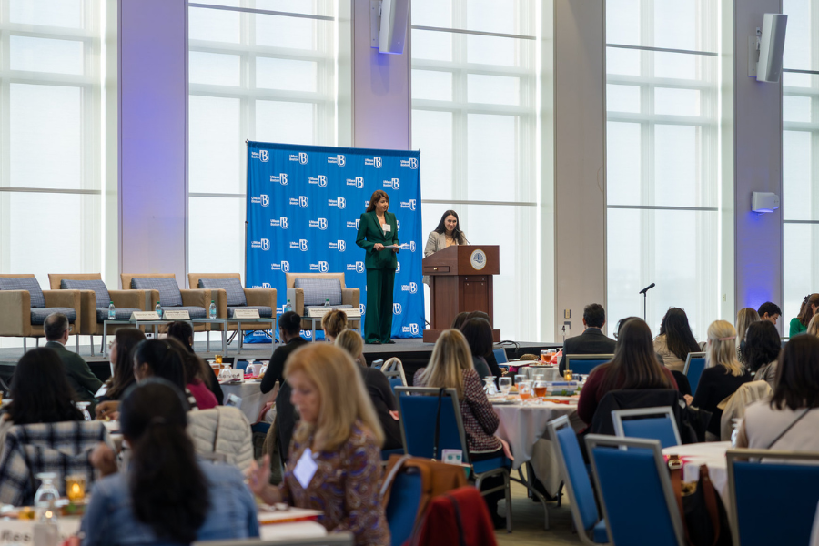 People sitting in the Campus Center Ballroom while a female student introduces herself.