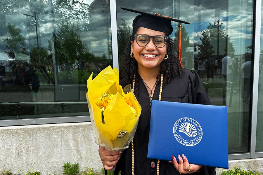 Ariyanna Roach, a 2026 graduate, poses with a bright yellow bouquet of flowers in front of the Campus Center