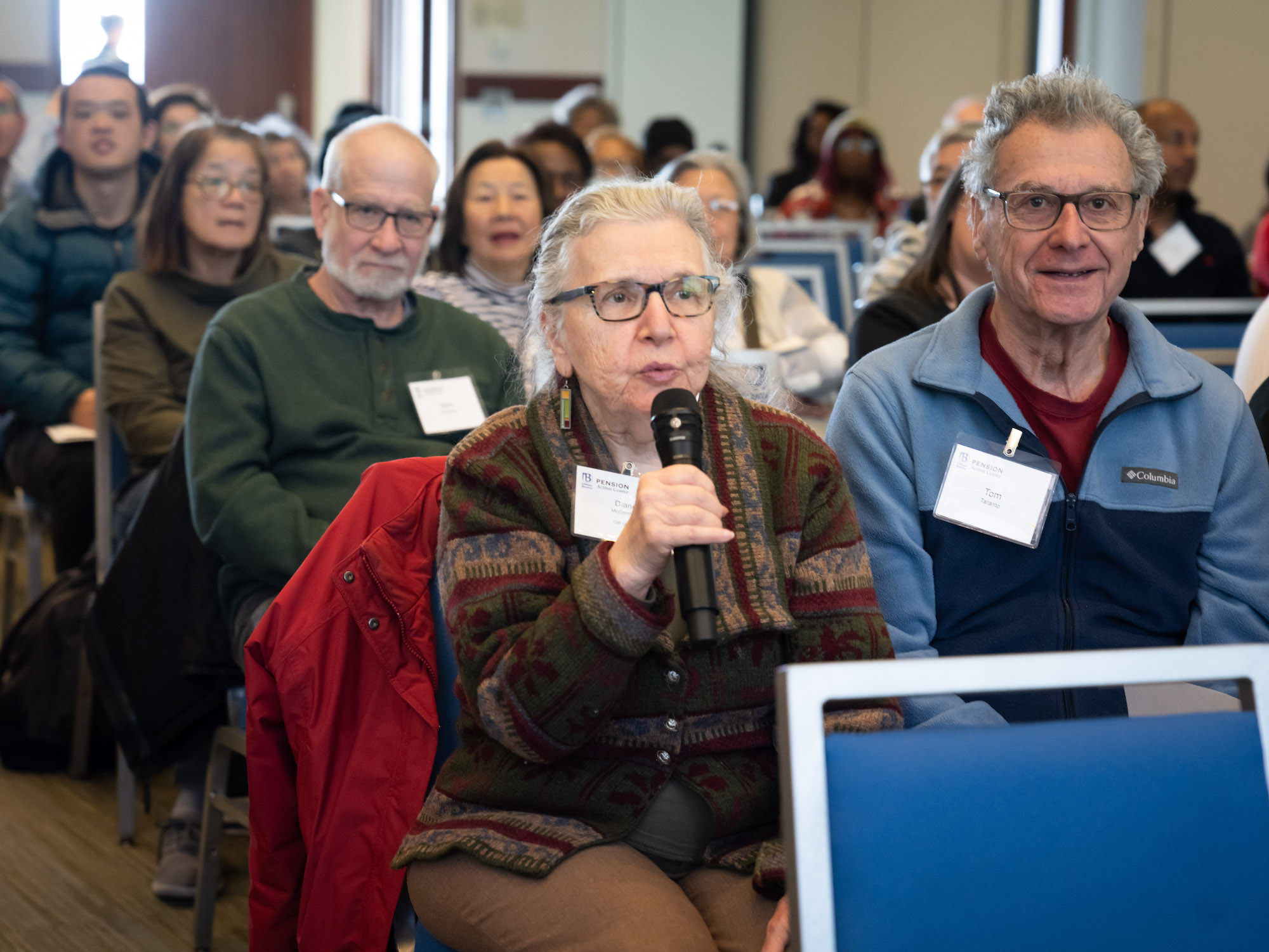 Elderly person with microphone at Fraud Prevention seminar