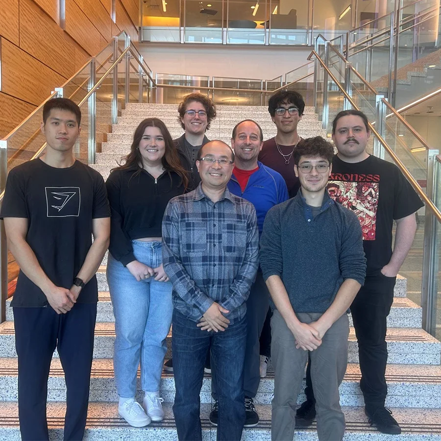 Zou lab staff stand with Kai Zou on the inside stairway in the Integrated Sciences Complex.