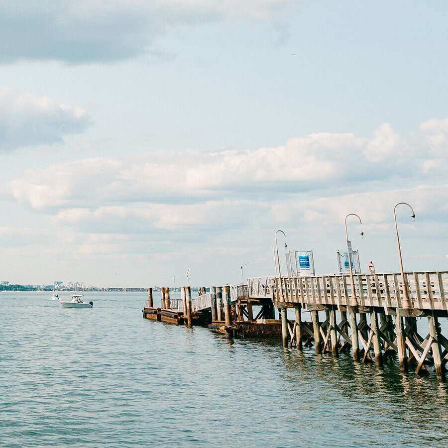 Wooden pier in the water with boat in the distance.