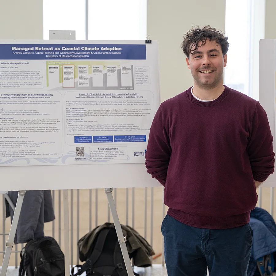 Student presents research on poster board at Earth Day symposium UMass Boston.