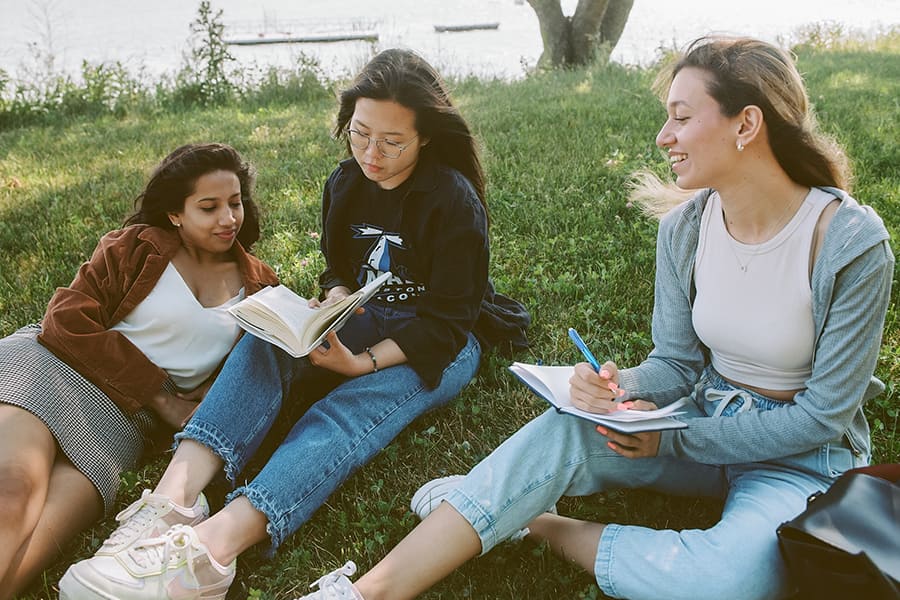 Three girls study. under a tree.