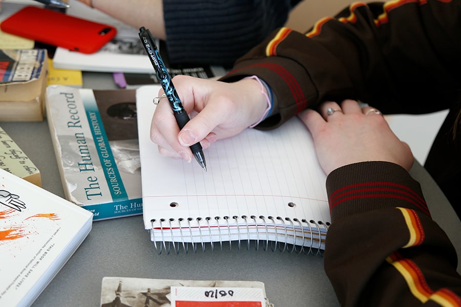 student writes in a notebook in university hall.